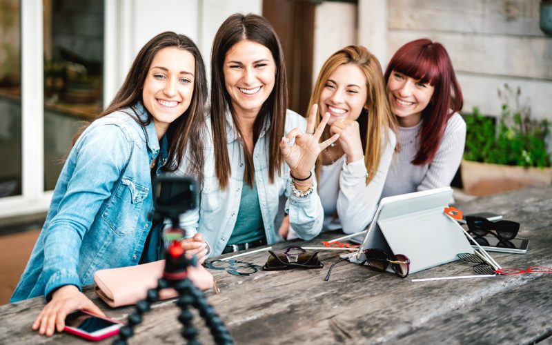 Gen z women having fun vlogging  story on social media platform with action web cam - Influencer marketing concept about millenial girls sharing content by streaming live feeds - Bright vivid filter