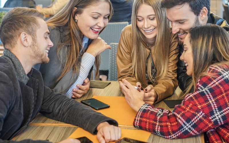 Group of friends watching mobile phones and having fun