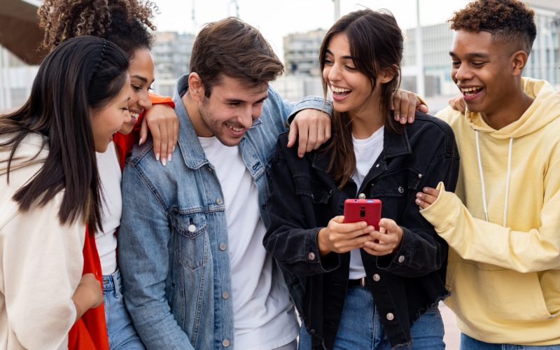 Group of young diverse smiling millennial friends looking at a mobile phone having a good time. having fun. High quality photo