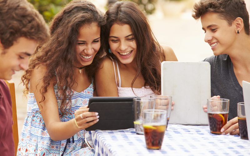 Teenage Friends Sitting At Caf Using Digital Tablets