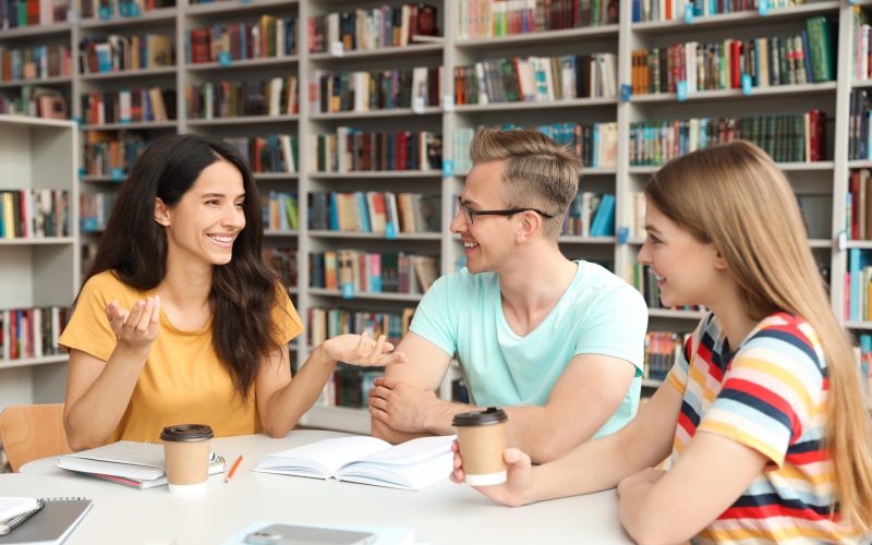 Young people discussing group project at table in library